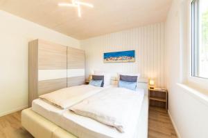a bedroom with a large white bed and a window at Ferienhaus Eastside - Niendorf in Häven