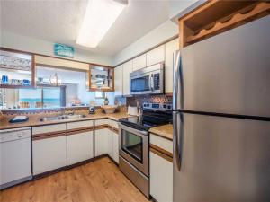 a kitchen with a stainless steel refrigerator and white cabinets at Ocean Dunes 2112 in Kure Beach