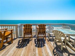 three chairs and a table on a deck with the ocean at Ocean Dunes 2112 in Kure Beach