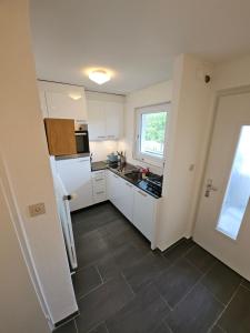 a kitchen with white cabinets and a tile floor at Sensi Living Stadion Self Check In in Rapperswil-Jona