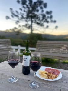 a table with two glasses of wine and a plate of food at Chalés Cantinho do Céu in Monte Verde
