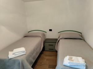two beds in a small room with towels on them at Piazza Varese in Valentano