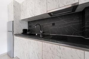 a black kitchen with a sink and a refrigerator at Central Square View Flogita in Flogita +27 photos