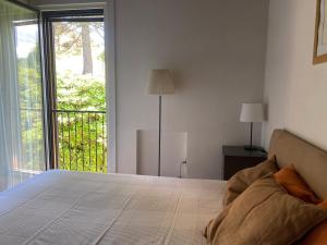 a bedroom with a bed and a large window at Motta Verde con piscina e tennis in Brisino +29 photos