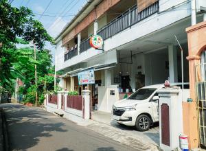 日惹Anjuma Backpacker的一辆白色汽车停在一栋建筑物前