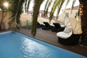 a pool with chaise lounges and chairs next to a swimming pool at Palacio Ramalhete in Lisbon