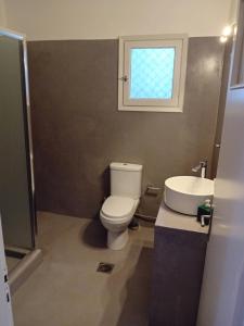 a bathroom with a toilet and a sink and a window at Lilian 2 in Batsi