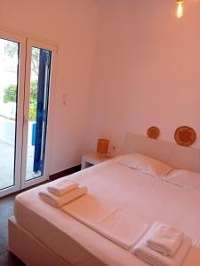 a white bedroom with a bed and a large window at Lilian 2 in Batsi +7 photos