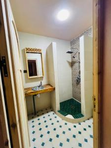 La salle de bains est pourvue d'une douche, d'un lavabo et d'un miroir. dans l'établissement Hiking Nomads Guesthouse, à Tamellalt