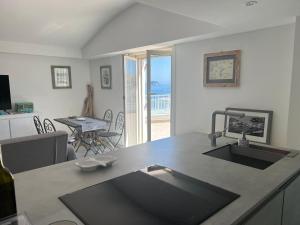 a kitchen with a sink and a living room with a table at Agenzia Isotur ATTICO SUL PORTO in Ponza