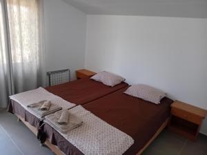a bed with two pairs of shoes sitting on it at Къща за гости АлеЯ in Kranevo