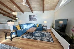 ein Wohnzimmer mit einem blauen Sofa und einem Fernseher in der Unterkunft Ocean Front, Eagle at the Oregon House, Stairs to the Beach! in Searose Beach