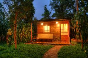 a small wooden cabin with a bench in the yard at Beverly Hill Cabanas Hikkaduwa in Hikkaduwa