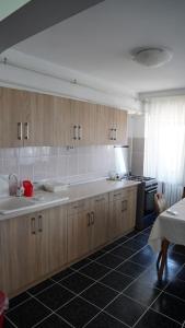 a kitchen with wooden cabinets and a black tile floor at Apart Portul Turistic in Mangalia +4 photos
