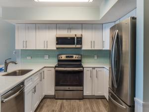Una cocina con gabinetes blancos y un refrigerador de acero inoxidable. en Pelican Watch #806, en Carolina Beach