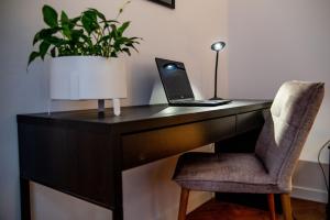 a desk with a laptop and a chair with a plant at Apartments Częstochowa - Słoneczna Kamienica - Centrum - Prywatny Parking free! - Klimatyzacja ! in Częstochowa
