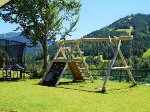 a wooden playground with a slide in the grass at Alte Schmiede in Balderschwang