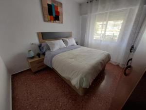 ein Schlafzimmer mit großem Bett und Fenster in der Unterkunft Apartamento en Playa de Bellreguard in Bellreguart + 8 Fotos