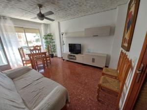 ein Wohnzimmer mit einem Bett, einem TV und Stühlen in der Unterkunft Apartamento en Playa de Bellreguard in Bellreguart