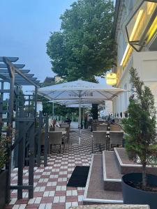 a patio with tables and chairs and an umbrella at Hotel Deutsches Haus Restaurant Olympia in Magdeburg