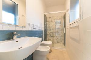 a white bathroom with a sink and a toilet at Villa Gioiello CENTRO in Favignana