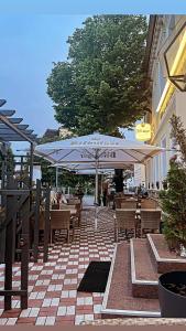 a patio with tables and chairs and an umbrella at Hotel Deutsches Haus Restaurant Olympia in Magdeburg