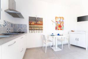 a white kitchen with a white table and chairs at Villa Gioiello CENTRO in Favignana +20 photos