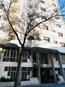 a building with a tree in front of it at Céntrico y amplio departamento en La Cañada in Cordoba +4 photos