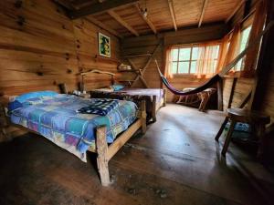 a bedroom with a bed and a hammock in a cabin at Paraiso Verde in Chijoú