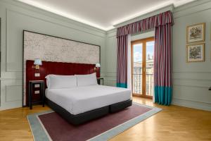 a bedroom with a white bed and a window at Room Mate Collection Isabella, Florence in Florence