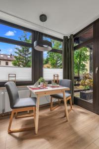 a dining room with a table and chairs and large windows at HIRSCH Stadt Apartment 1 - Terrasse mit Flussblick - Parkplatz in Bad Harzburg