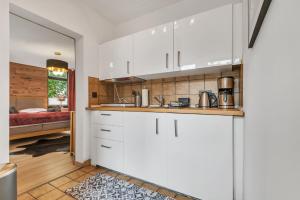 a kitchen with white cabinets and a bedroom at HIRSCH Stadt Apartment 1 - Terrasse mit Flussblick - Parkplatz in Bad Harzburg