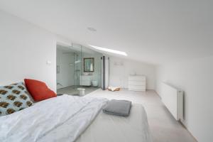 a white bedroom with a large bed and a bathroom at Black & White Apartments Rožna dolina in Ljubljana