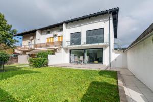 a white house with a lawn in front of it at Black & White Apartments Rožna dolina in Ljubljana