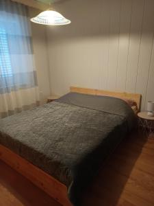 ein Schlafzimmer mit einem Bett mit einer grauen Bettdecke in der Unterkunft Apartments Knežević in Jadranovo