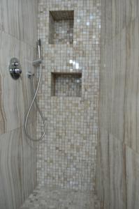 a shower in a bathroom with a tile wall at Appartamenti Piazza Duomo Acireale in Acireale