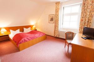 a bedroom with a bed and a desk and a television at Hotel Alter Wolf in Wolfsburg