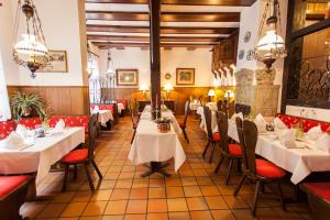 a restaurant with white tables and red chairs at Hotel Alter Wolf in Wolfsburg