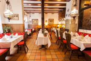 ヴォルフスブルクにあるHotel Alter Wolfの白いテーブルと赤い椅子が備わるレストラン