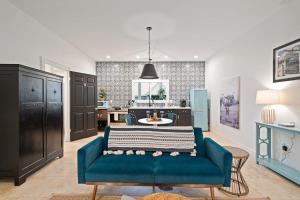 a living room with a blue couch and a kitchen at Stonewall Bungalows - Sleeps 15 in Stonewall