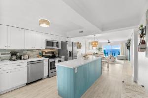 a kitchen with white cabinets and a blue island at 4 Loungers 2 Umbrellas Inlc Peak Season Beachfront in Panama City Beach