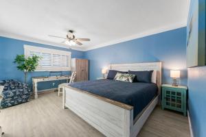 a bedroom with a bed and a blue wall at 4 Loungers 2 Umbrellas Inlc Peak Season Beachfront in Panama City Beach +34 photos