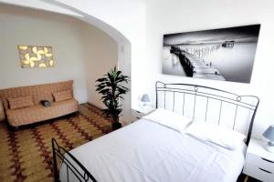 Casa Arcobaleno - giardino e parcheggio gratuito في لا سبيتسيا: غرفة نوم بسرير ابيض واريكة