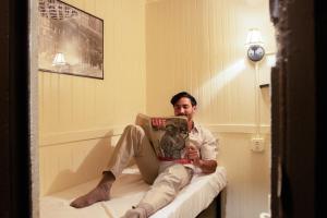 Un uomo seduto su un letto che legge un libro di The Nolita Express Hostel a New York