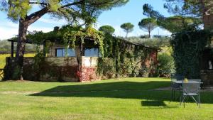 ein mit Efeu bedecktes Haus mit einem Tisch und Stühlen im Gras in der Unterkunft Poggio alle Vigne in Torgiano