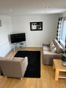 a living room with a couch and a tv at Highland Holiday Lets Lairg in Lairg