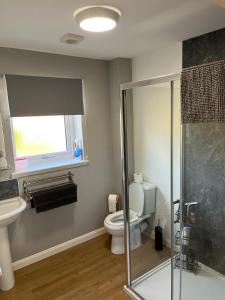 a bathroom with a shower and a toilet and a window at Highland Holiday Lets Lairg in Lairg