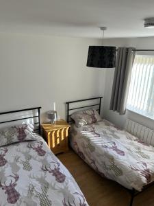 a bedroom with two beds and a window at Highland Holiday Lets Lairg in Lairg