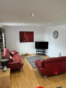 a living room with red leather furniture and a flat screen tv at Highland Holiday Lets Lairg in Lairg +2 photos