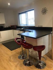a kitchen with a black counter and two red bar stools at Highland Holiday Lets Lairg in Lairg